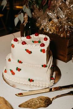 a three tiered cake with cherries on it sitting on top of a table