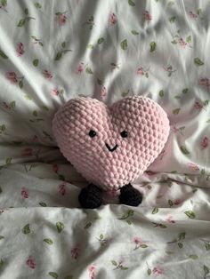 a pink stuffed heart sitting on top of a bed