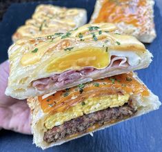 a hand holding a sandwich with meat and cheese