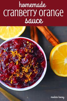 a white bowl filled with cranberry sauce next to sliced oranges and cinnamon sticks