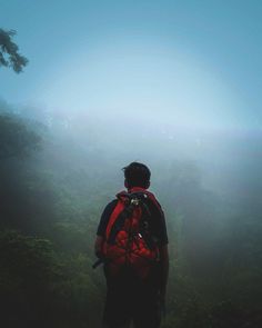 a man with a backpack is standing in the fog