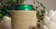 a crocheted coffee cup cozying in front of a plant