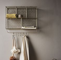 two towels hanging from hooks on the wall next to towel rack and other items in front of it