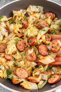 sausage, cabbage and pasta in a skillet with wooden spoons on the side