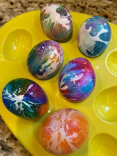 six painted eggs sitting on top of a yellow tray