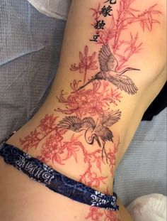 a woman's lower back tattoo with birds and flowers on her stomach, in chinese writing