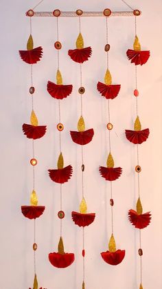 a red and gold wind chime hanging from a white wall