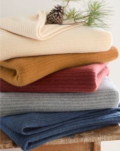 a stack of folded sweaters with pine cone on top