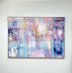 an abstract painting hanging on the wall in a white walled room with blue, pink and yellow colors