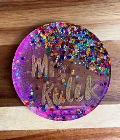 a plate that has confetti on it and the words mrs kuak spelled in gold