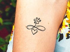 a dog paw and heart tattoo on the left inner arm, which is drawn in black ink