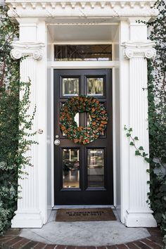 a black front door with a wreath on it