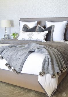 a large bed with white and gray pillows