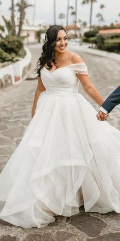 a bride and groom hold hands while walking down the street in front of palm trees