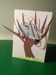 a card with a blue car stuck to the side of a tree that has been cut out