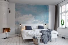 a white bed sitting in a bedroom on top of a hard wood floor next to a window