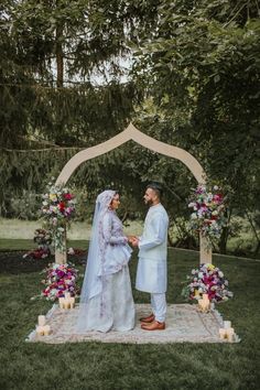 a bride and groom standing under an arch with candles