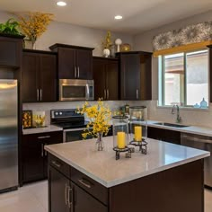 a kitchen with dark wood cabinets and stainless steel appliances, yellow flowers in vases on the counter