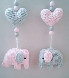 two crocheted elephants hanging from strings with heart shaped balloons attached to the string