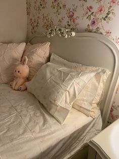 a stuffed animal sitting on top of a bed next to pillows and pillowcases