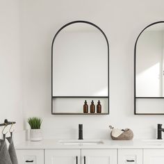 two mirrors are hanging on the wall above sinks in a white bathroom with black trim