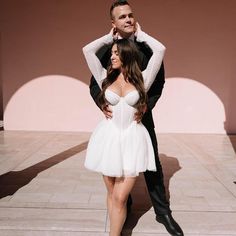 a man standing next to a woman in a white dress