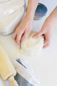 a person kneading dough on top of a counter next to a rolling pin