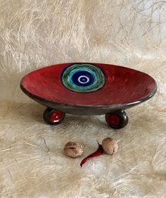 a red and blue plate sitting on top of a white fur covered floor next to nuts