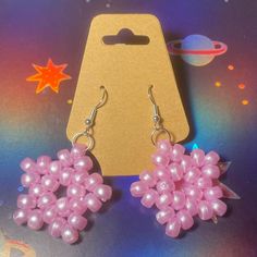 pair of pink beaded earrings sitting on top of a purple card board with space in the background