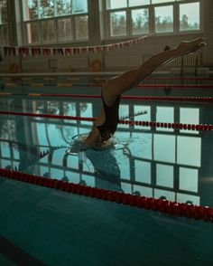 a woman in a swimming suit is doing a trick on the edge of a pool