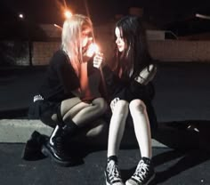 two young women sitting on the ground with one holding a lit candle in her hand