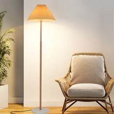 a chair sitting next to a lamp on top of a hard wood floor near a potted plant