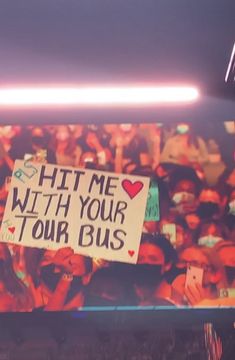 a sign that says hit me with your tour bus in front of a large crowd