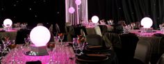 tables and chairs are set up for an event with pink lights in the centerpieces