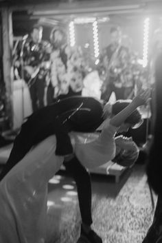 a woman in black and white dancing on the dance floor with other people behind her