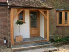 a house with a door and steps leading up to the front entrance, next to a small tree