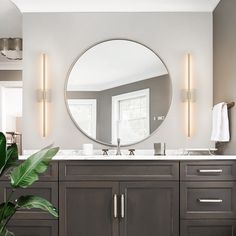 a bathroom with a large round mirror above the sink and two lights on the wall