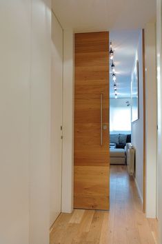 an open door leading to a living room and dining area with hardwood floors, white walls and wood flooring