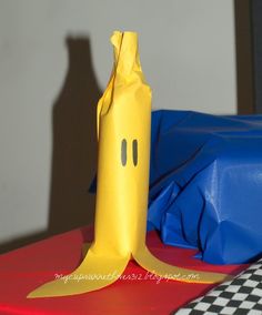 a paper bag that looks like a banana sitting on top of a red and blue table cloth