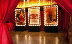 the stage is decorated with red drapes and lights for an event or show in which there are posters on the walls