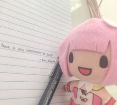 a stuffed animal sitting next to a notepad with writing on it and a pen