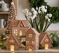 a group of gingerbread houses sitting on top of a table next to white flowers