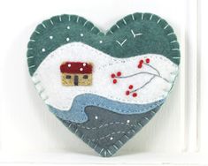 a heart shaped decoration hanging on the side of a white door with a house in it