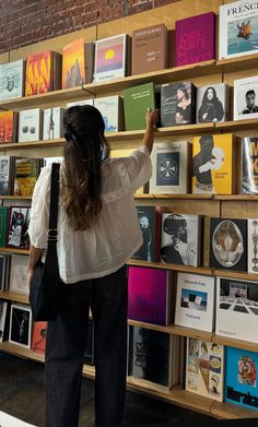 a woman standing in front of a book shelf filled with books