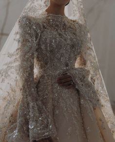 a woman in a wedding dress with a veil on her head and hands behind her back