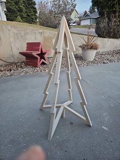 a wooden christmas tree sitting on top of a cement ground