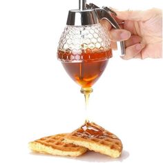 a person pouring syrup into a glass with waffles