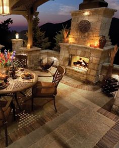 an outdoor dining area with stone fireplace and seating