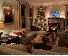 a living room filled with furniture and a christmas tree in front of a fire place