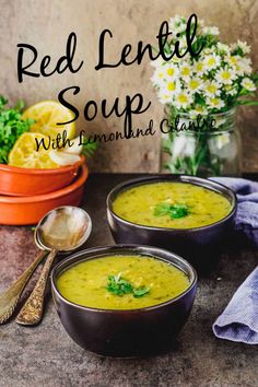 two bowls of red lentil soup with lemon and basil garnish on the side